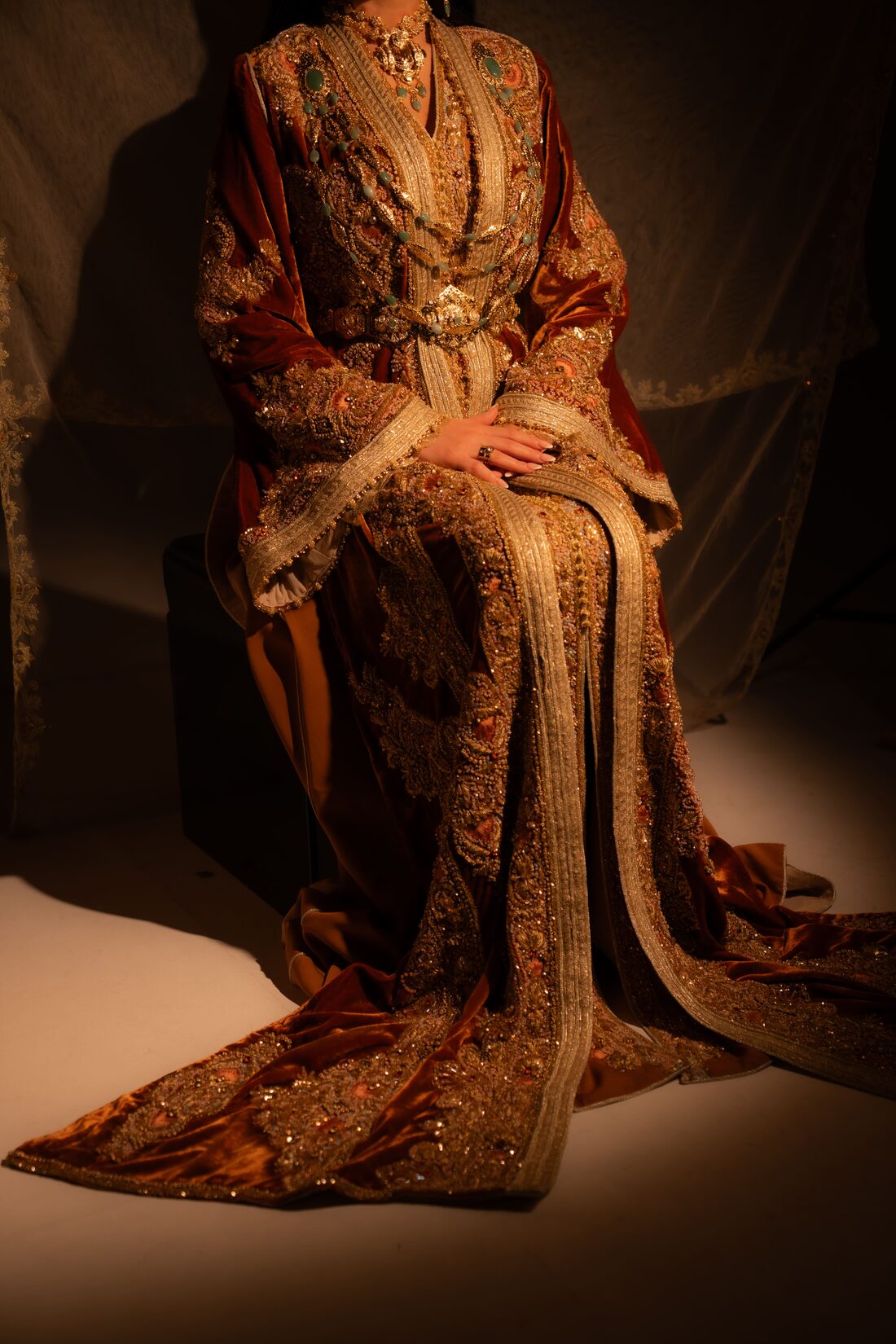 Mariée assise en caftan de velours bordeaux et broderies dorées